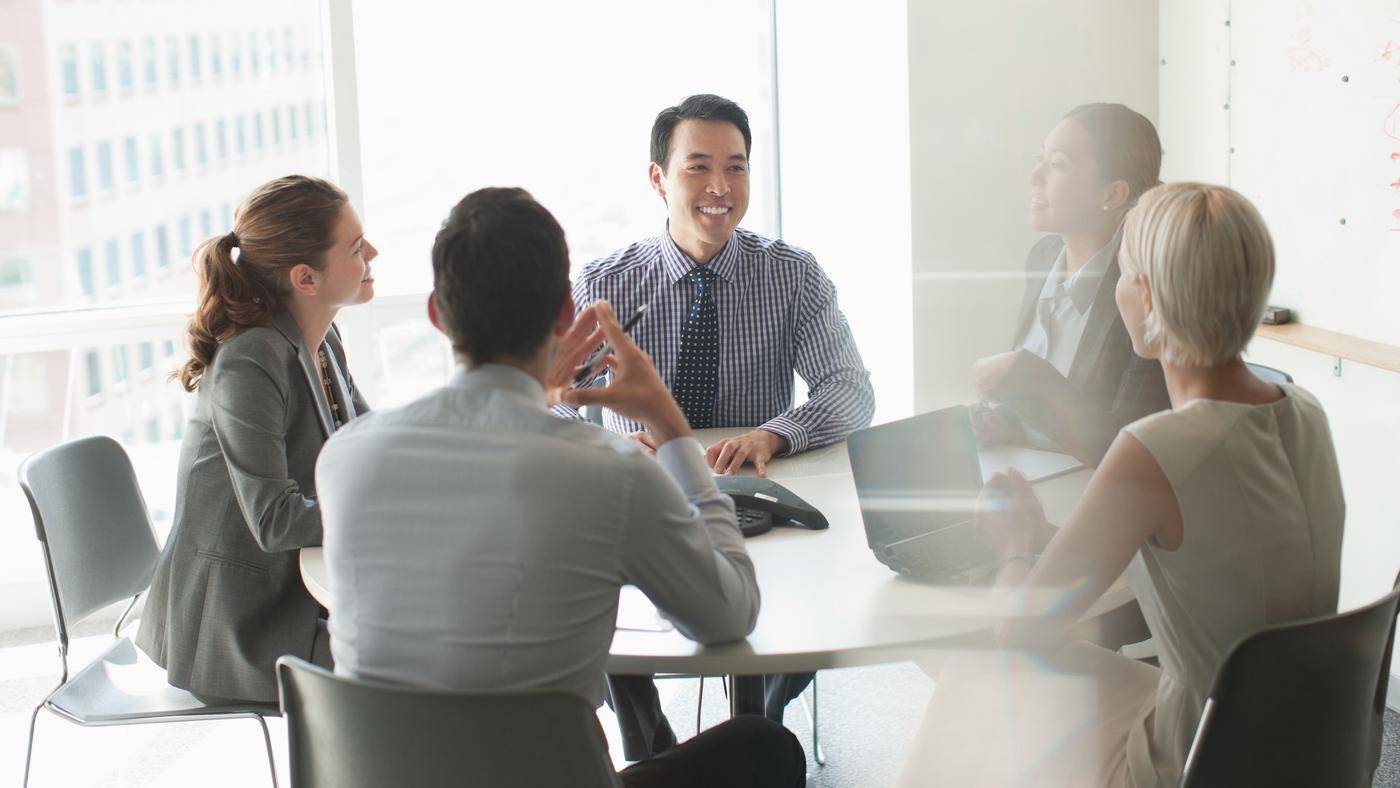 A group of business people are all smiling and having a meeting in a conference room.