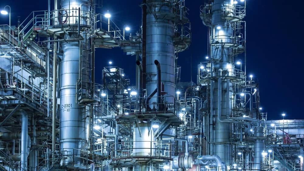 An illuminated gas/oil refinery at night.