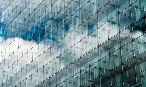Blue clouded sky reflected in glass frontage of a modern glass building.