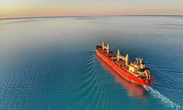 Lone empty container ship in an open expanse of water.