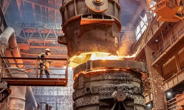 A worker is smelting metal on a raise platform in an industrial factory.