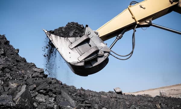 An excavator is scooping coal out of a pile.