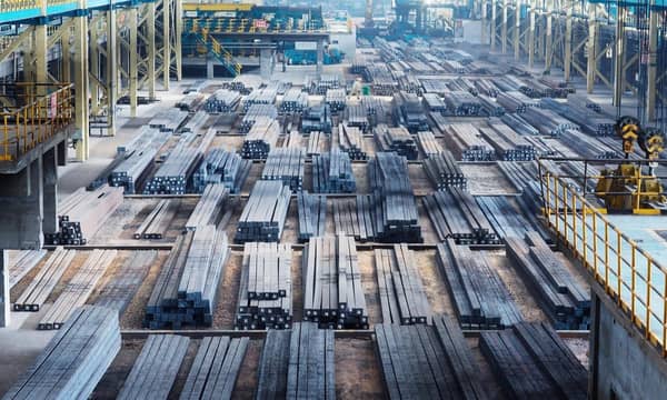 A large open factory with vast amounts of steel beams lined up.