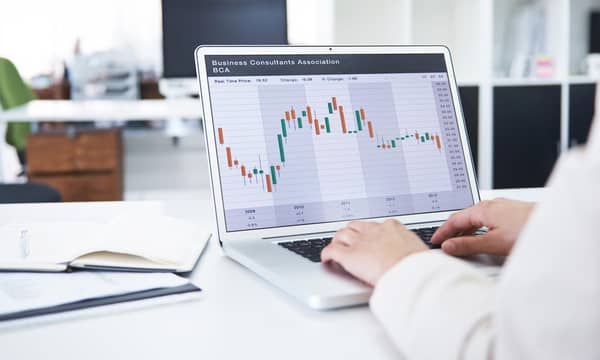 Rearview shot of a  businesswoman working with financial graphs on her laptop, in an office environment.