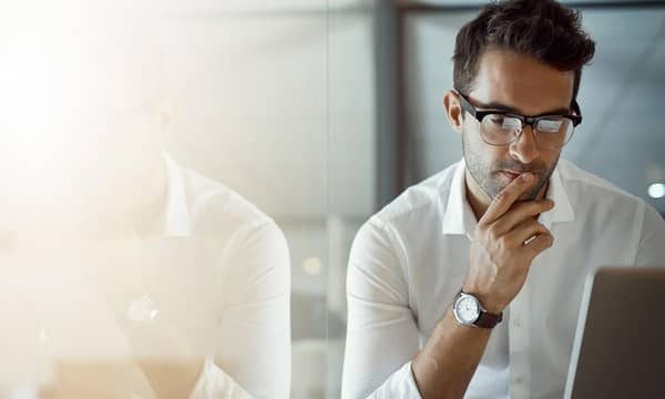 Cropped shot of a young businessman, looking thoughtful while working on his laptop in the office.