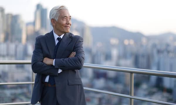 A man in a suit is standing on a balcony overlooking a city.