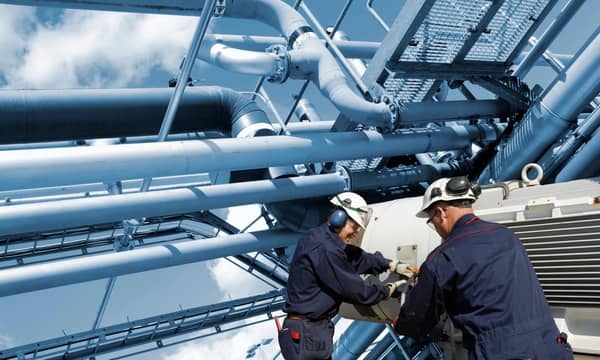 Two oil and gas workers with large fuel pipelines.