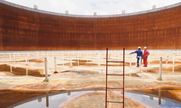 Technicians examining the interior of an empty fuel storage tank.