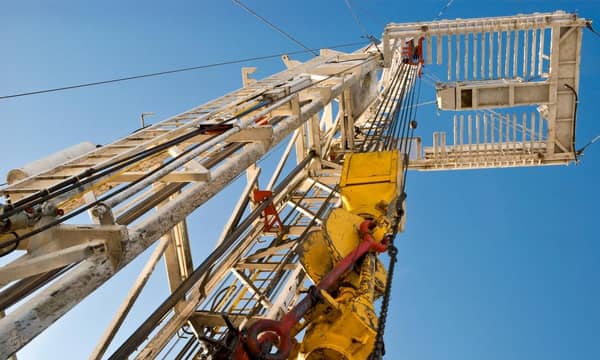 Upward view of a drilling section of an oil rig, blue sky in the background.