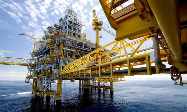 A close-up of a yellow and white oil platform in the middle of the ocean.