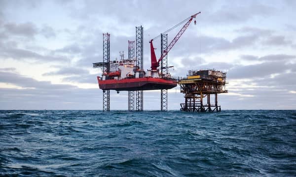 Two oil drilling rigs in open choppy waters.