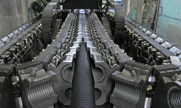 A close-up of a large mechanical conveyor belt, inside a factory.