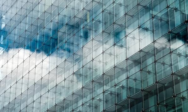 Blue clouded sky reflected in glass frontage of a modern glass building.