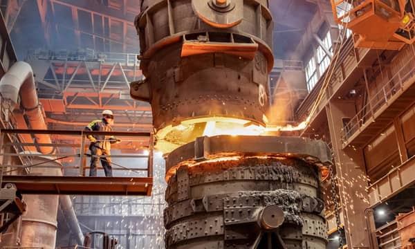 A worker is smelting metal on a raise platform in an industrial factory.
