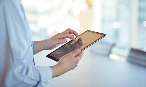 Corporate business still-life, in high-end office environment. Person using an iPad.