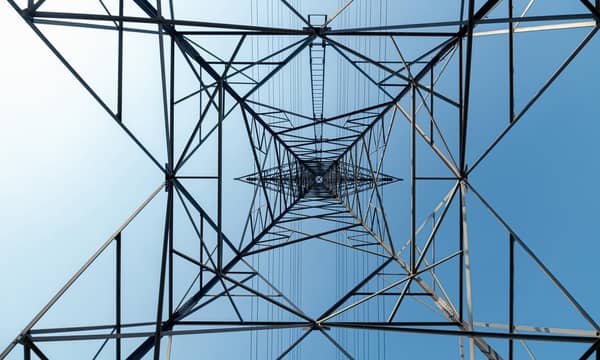 A view of the interior of a high voltage tower against a blue sky.