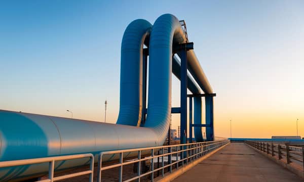 Blue pipes going to oil refinery from a port, during sunrise.