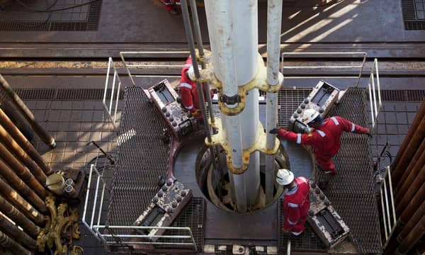 Aerial shot of engineers working a drill, atop an oil rig.