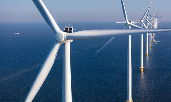 A close-up of a row of wind turbines in the open sea,