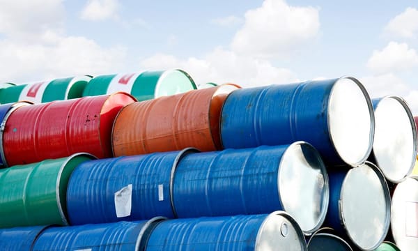 Stacked rows of red, green, blue and yellow oil drums.