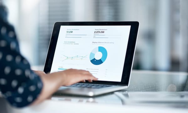 Cropped shot of a businesswoman using a laptop at her desk in a modern office, looking at data charts.