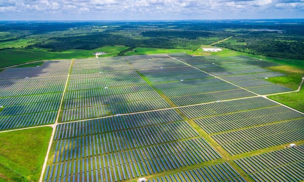 An aerial view of a vast solar farm spread across the countryside.