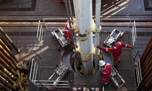 Aerial shot of engineers working a drill, atop an oil rig.