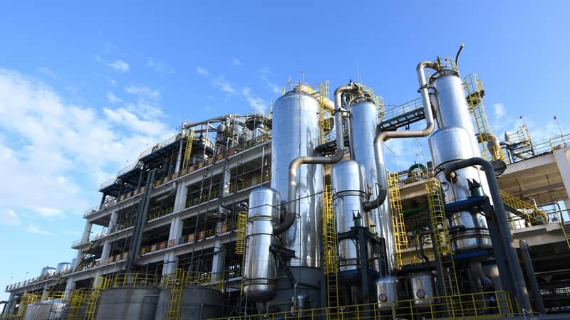 The exterior of a large industrial plant with many silver cylindric tanks, across multiple levels.
