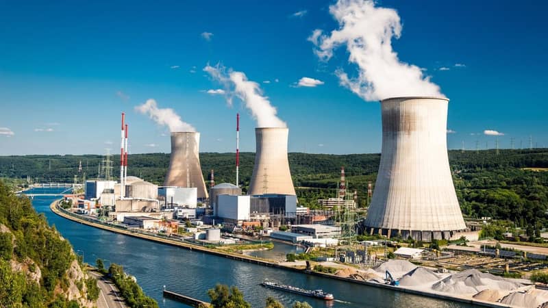 A nuclear power plant next to a river, in the countryside, on a clear blue day.
