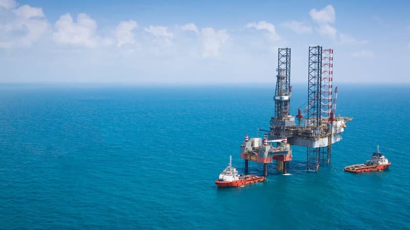 Two oil rigs and vessels in the middle of the ocean.