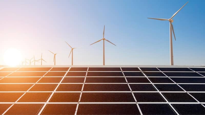 Solar panels and wind turbines on a sunny day.