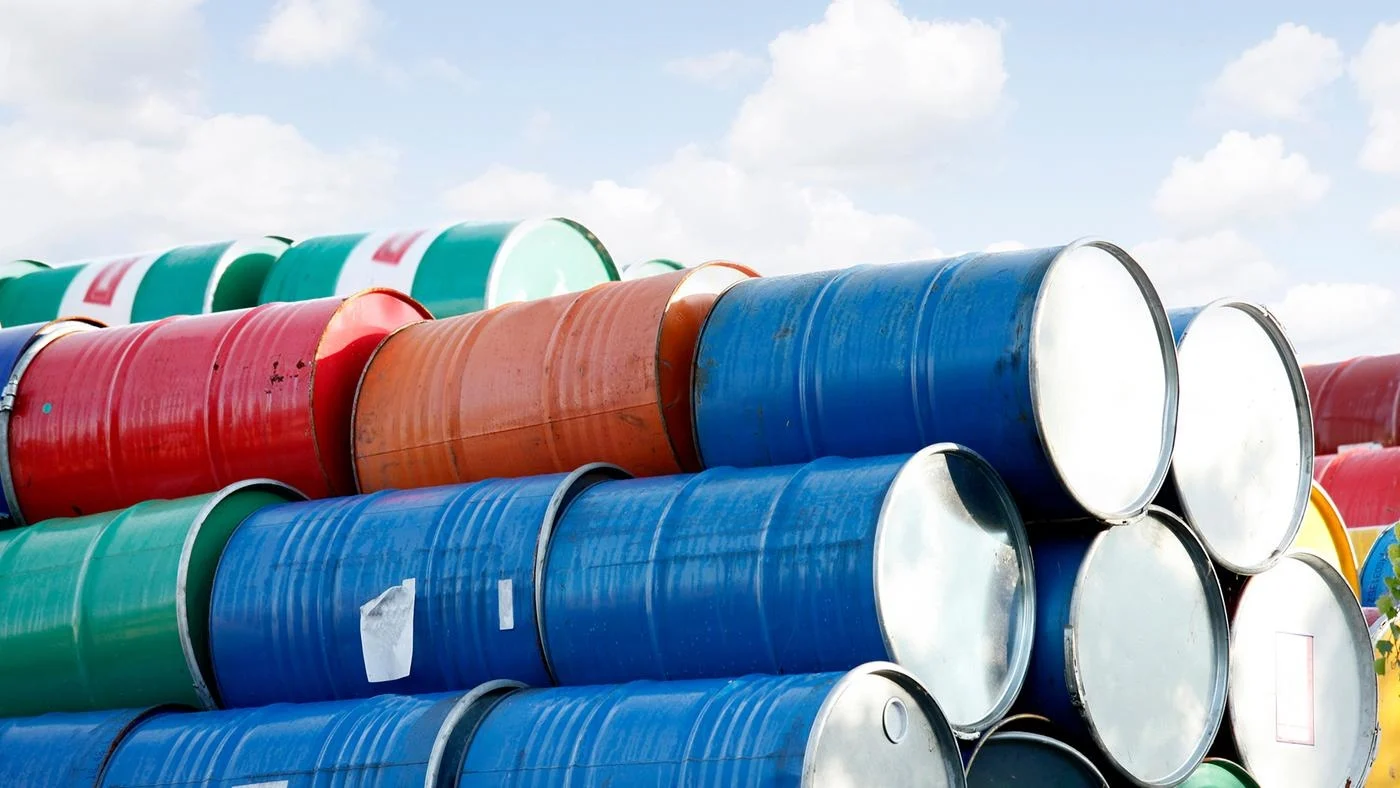 Stacked rows of red, green, blue and yellow oil drums.