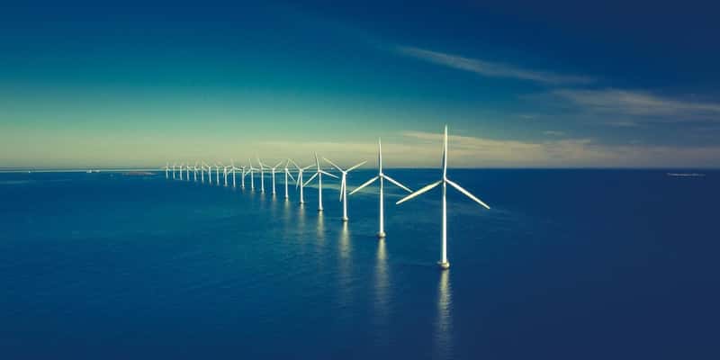 A row of wind turbines at sea.