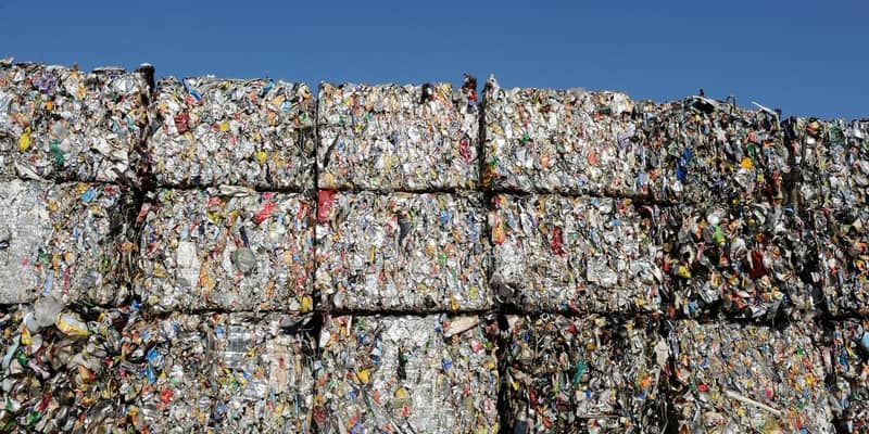 Multiple bales of plastic waste, piled high with a blue sky in the background.