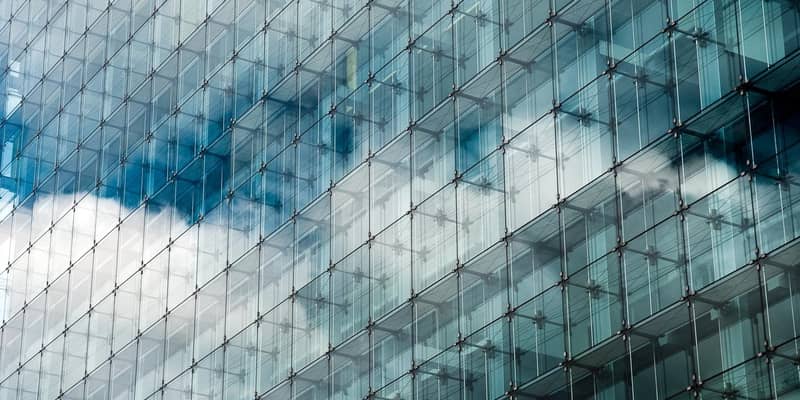 Blue clouded sky reflected in glass frontage of a modern glass building.