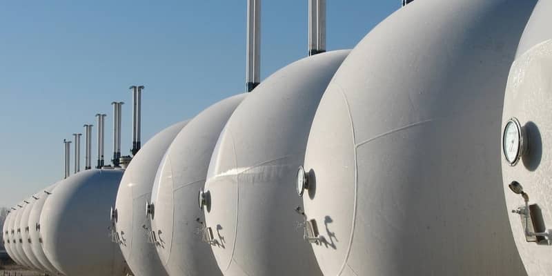 A row of white gas cylinders lined up in a field.