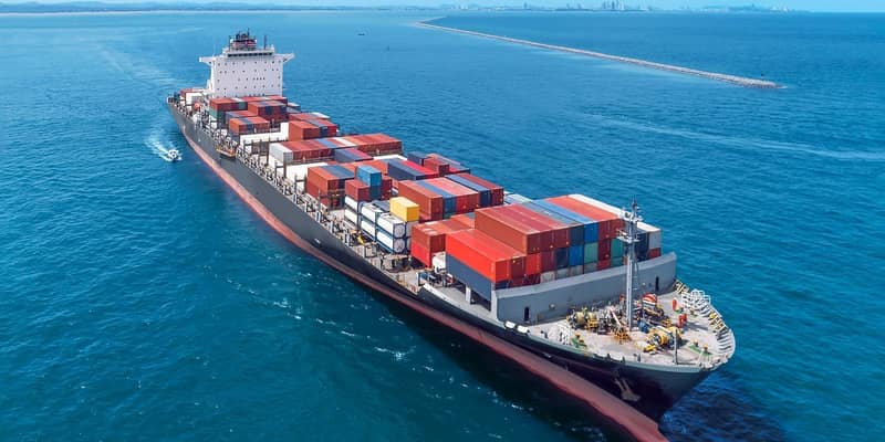 Aerial view of cargo ship running on sea close warehouse harbour at Thailand .