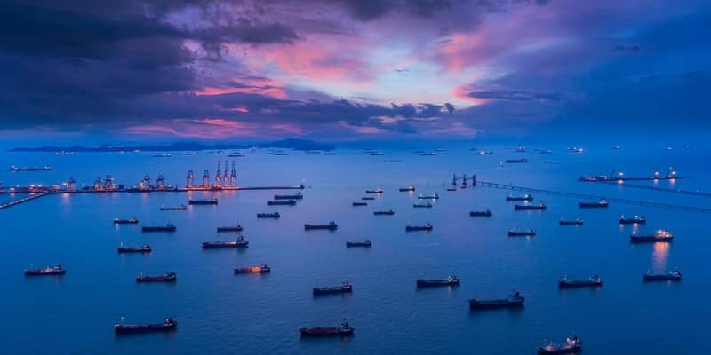 Aerial view Oil ship tanker park on the sea at dusk with beautiful sky waiting for load/unload oil from refinery for transportation.