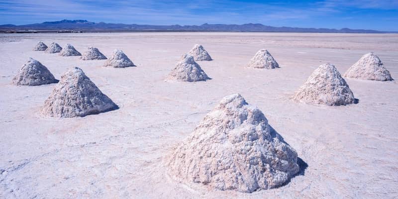 Several large cone-shaped piles of lithium deposits in the middle of a salt flat.