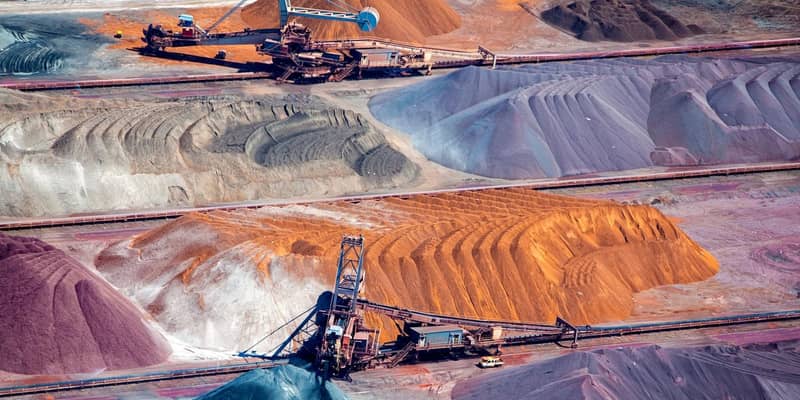 Two large excavators working piles of rocks.