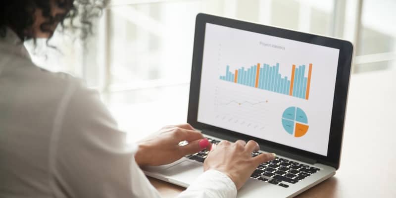 Businesswoman analysing statistics on laptop screen, working with financial graphs charts online, using business software for data analysis and project management concept, rear close up view