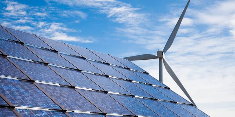 Solar panels and a wind turbine against a blue sky.