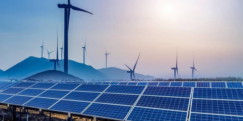 Solar panels and wind turbines in a field., surrounded by hills at dusk.