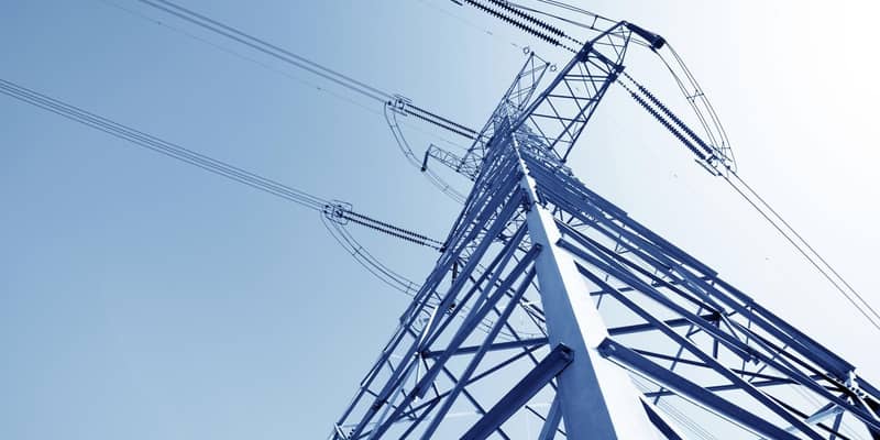A close up of a high voltage pylon against a blue sky.