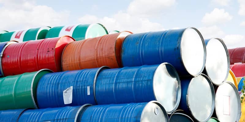 Stacked rows of red, green, blue and yellow oil drums.