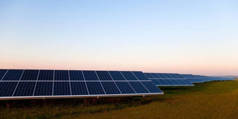 Rows of solar panels in a field,  blue sky in the background.
