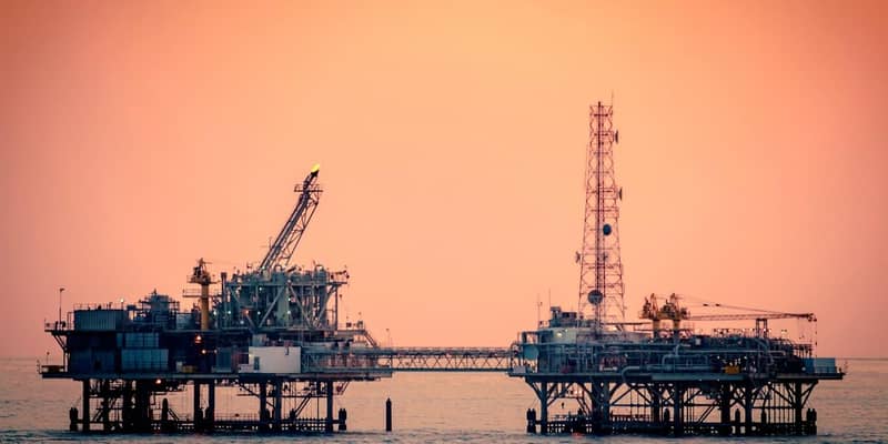 A close-up of two connected sections of an oil rig at sunset.