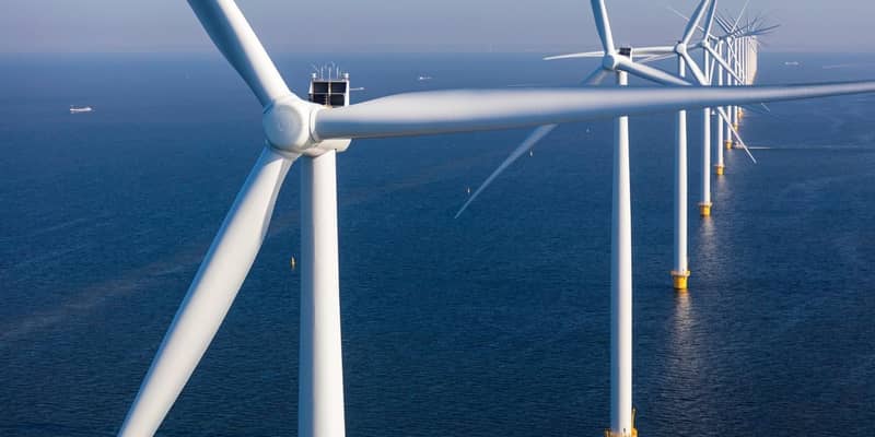 A close-up of a row of wind turbines in the open sea,