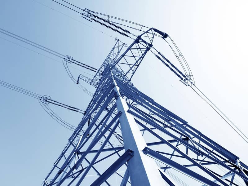 A close up of a high voltage pylon against a blue sky.