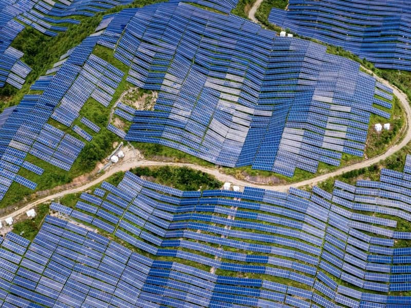 An aerial view of a countryside/hilltop solar farm.